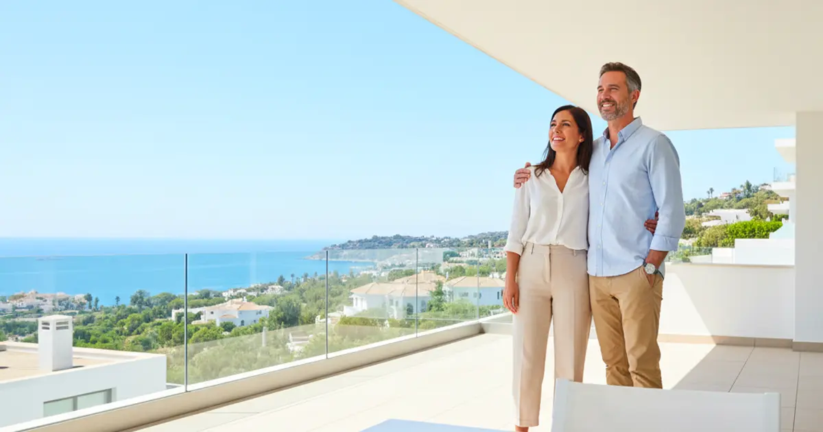 Happy couple viewing a modern house with sea view in Spain, illustrating financing options for foreigners and US buyers in 2025